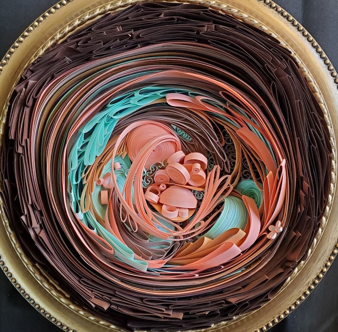 Growing from Peach Nostalgia: a round piece in a gold frame, with swirls of chocolate-brown, peach and teal paper strips