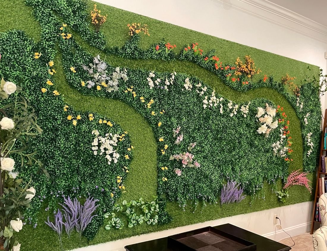 Georgia Office “Live” Wall: a long wall of green artificial foliage with white, yellow and purple flowers winding across it